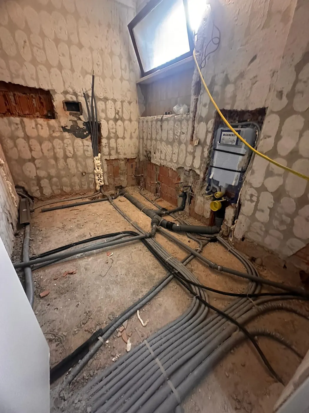 Bagno in cantiere con le tubazioni dell'impianto idraulico a pavimento